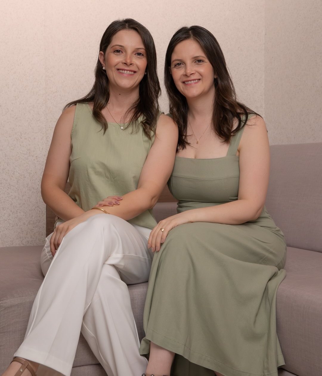 Heloisa e Helena Santos, irmãs gêmeas e psicólogas da HS Psicologia, sentadas juntas sorrindo